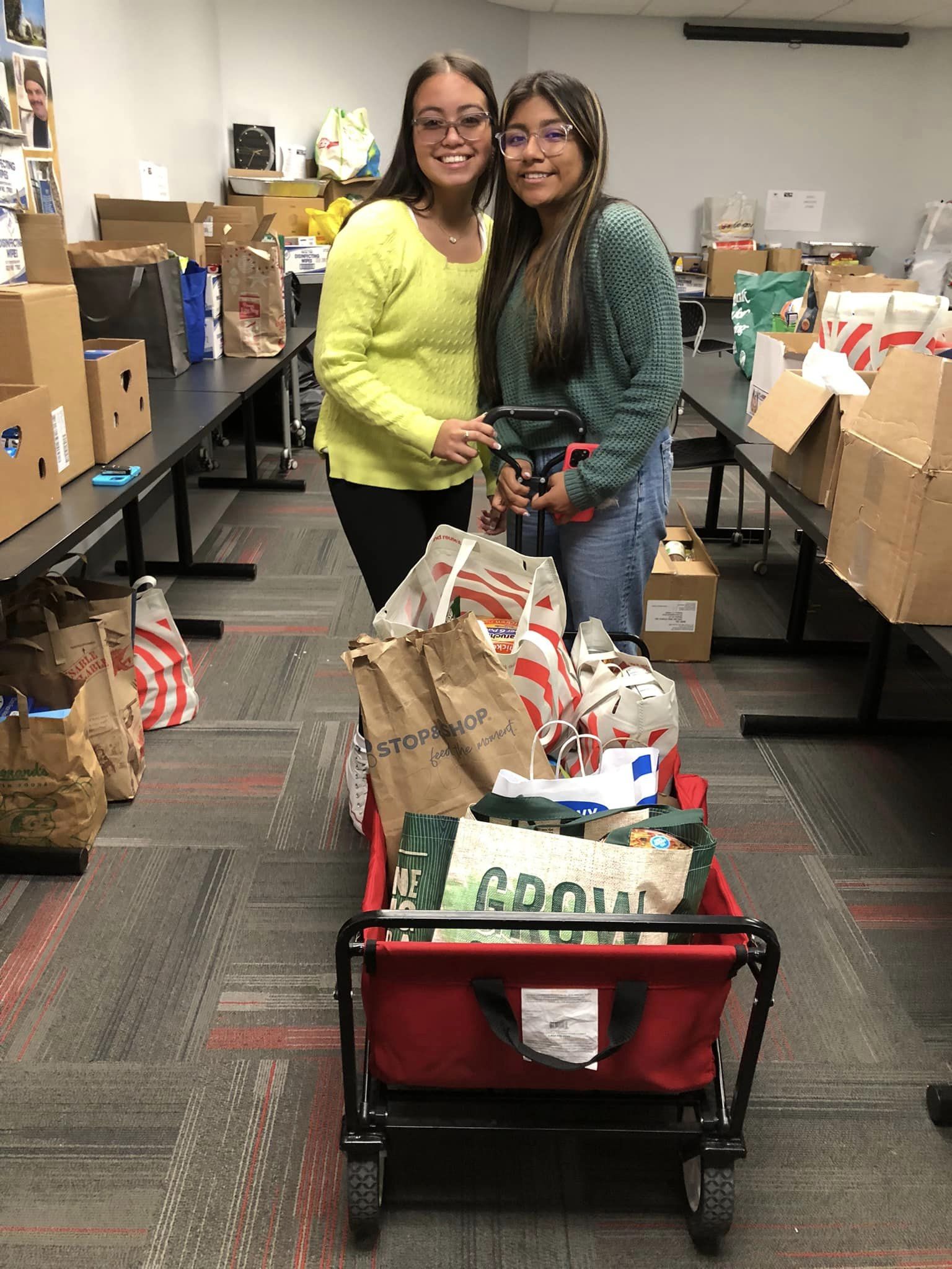 Two high school students with a wagon filled with nonperishable food