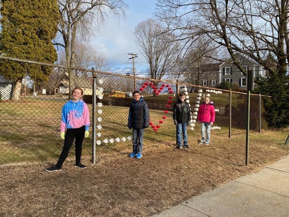 KIM students putting cups in chain link fence